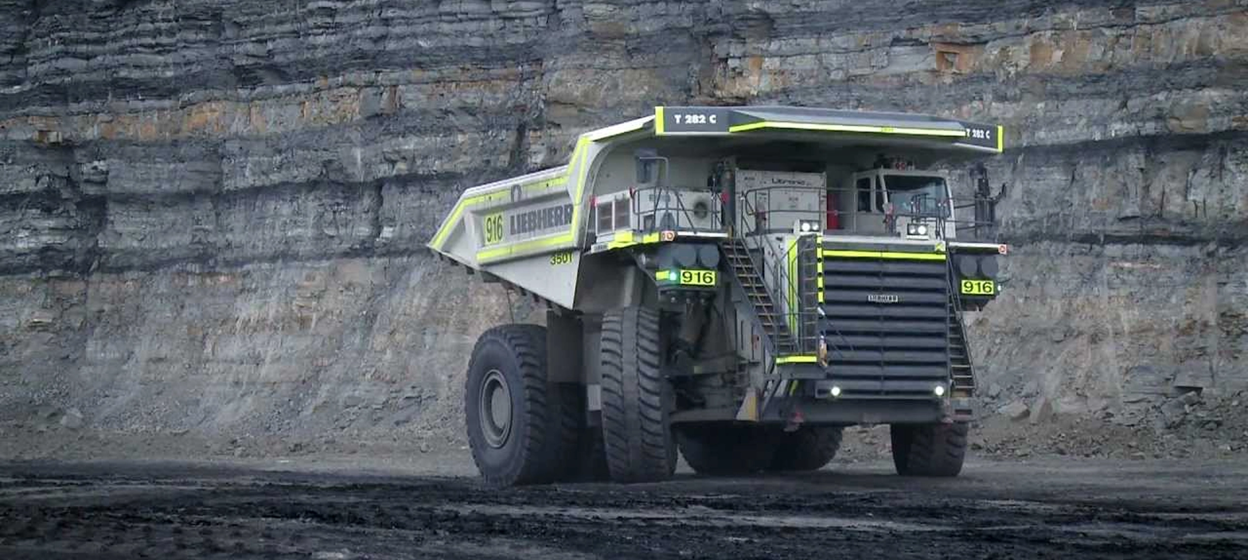 A very large truck used for mining sits parked with its wheels turned on a mining step.